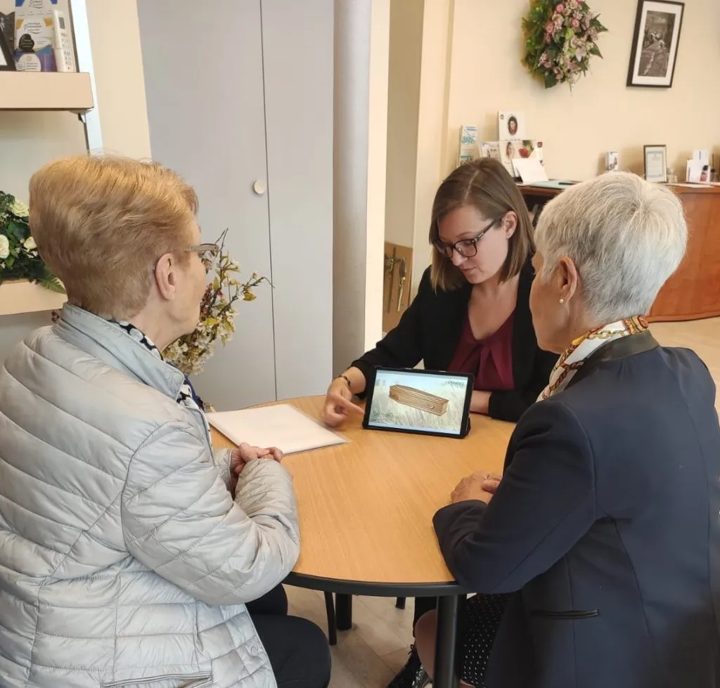 Conseillère funéraire présentant un contrat de prévoyance à des clientes sur tablette