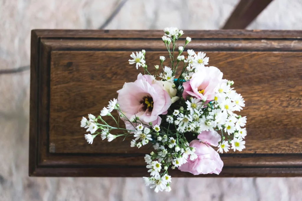 Bouquet de fleurs roses et blanches posé sur un cercueil en bois massif