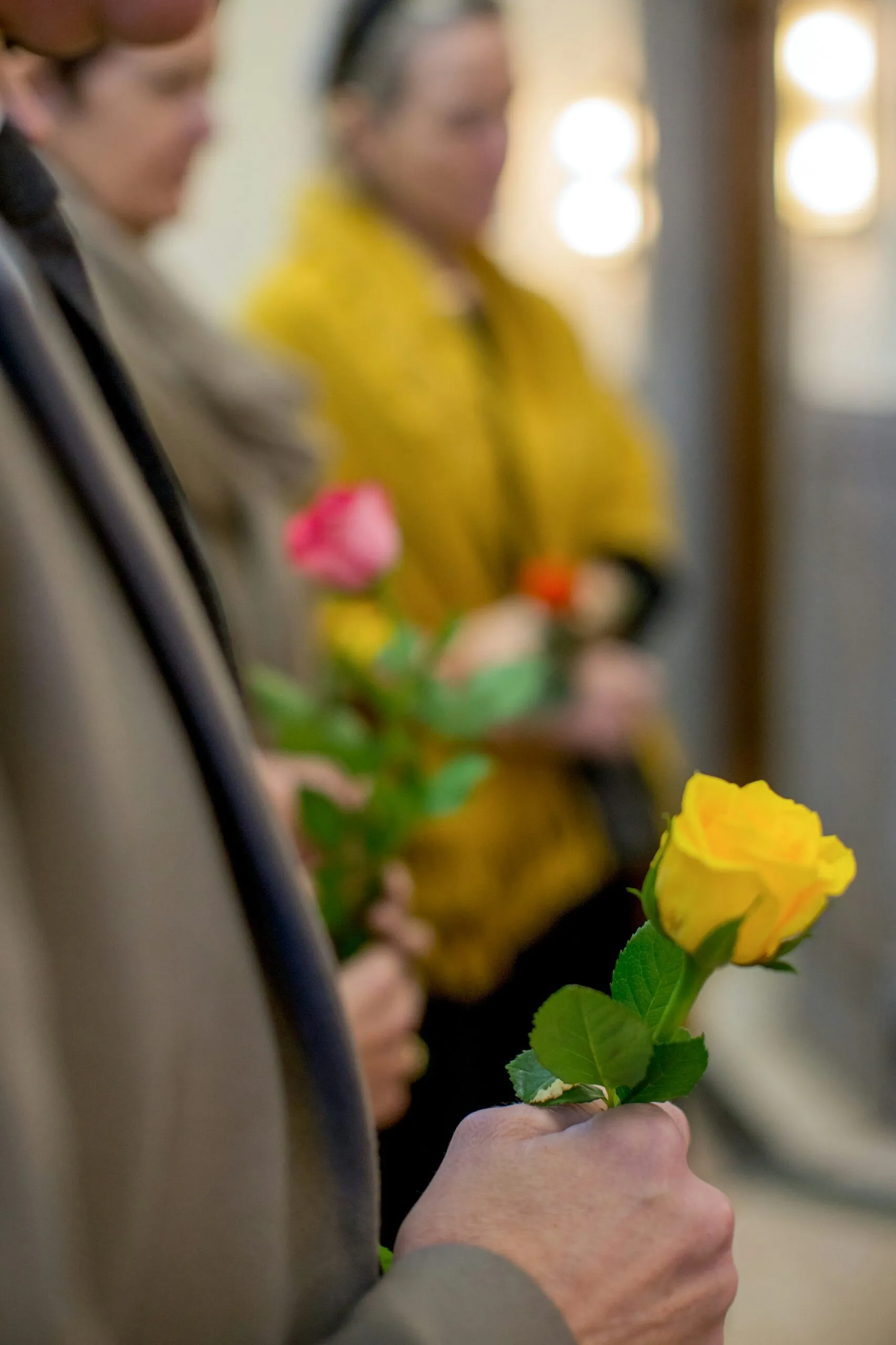 Proches tenant des roses jaunes et roses lors d'une cérémonie d'hommage funéraire