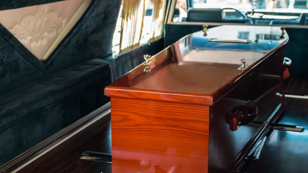 Cercueil en bois verni installé à l'intérieur d'un corbillard funéraire